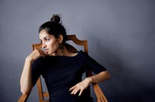 pretty woman earrings jewelry posing near the chair black dress isolated background photo