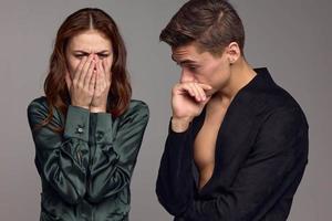 A puzzled man and an upset woman on a gray background are gesturing with their hands photo