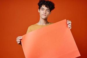 alegre hombre con Rizado pelo póster en manos publicidad estudio foto