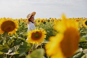 mujer retrato en un blanco vestir caminando en un campo de girasoles inalterado foto