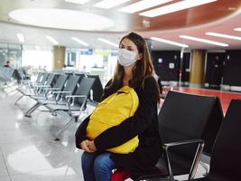 mujer sentado a el aeropuerto amarillo mochila esperando vuelo retrasar insatisfacción foto