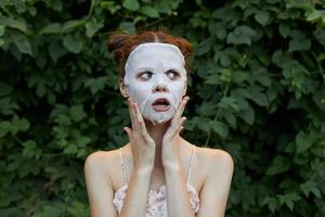 Portrait of a girl cosmetic mask Surprised to touch your face with your hands dermatology bushes in the background photo