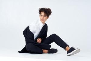 chico sentado en el piso Rizado pelo traje moderno estilo foto