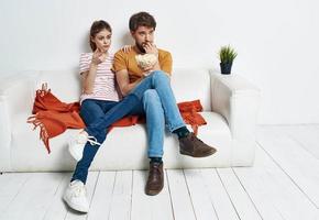 Couple in love with popcorn and watching TV while on the couch indoors photo