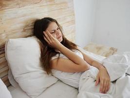 woman with headache lies in bed temperature health problems photo