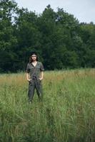 Woman on nature holds his hands in the pockets of green overalls in the meadow photo