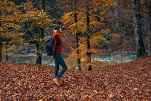 un viajero con un mochila camina en el parque en naturaleza cerca el río en otoño foto