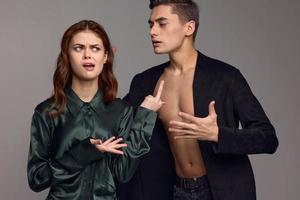 Conflict situation young people in suits on a gray background gestures with their hands problems in the family photo