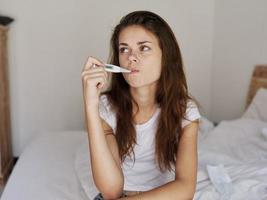 woman with a thermometer in her mouth waiting for the temperature result photo