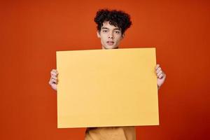 emotional man with curly hair yellow poster in hands photo