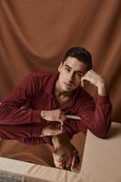 A nice guy sits at a table near a mirror on a fabric background photo