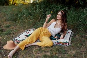 joven hermosa hippie mujer acostado en el suelo en naturaleza en el otoño en eco ropa en amarillo pantalones en el puesta de sol ligero foto