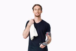 handsome male athlete with a towel on his shoulder and dumbbells in his hand photo