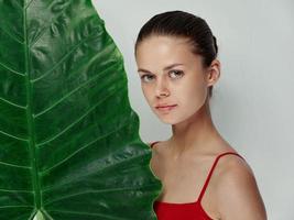 woman in red swimsuit with palm leaf cropped view light background photo