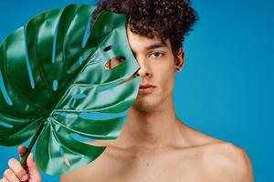 handsome man with curly hair naked shoulders green leaf clear skin photo