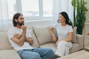 Male and female Asian friends sitting on the couch and having fun talking to each other with a smile having a good time together. Lifestyle in happiness at home photo