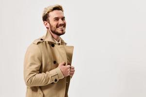 cheerful man in a coat holds on to the collar smile studio lifestyle photo