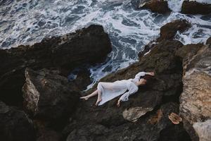 sensual woman in a secluded spot on a wild rocky coast in a white dress landscape photo