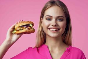 linda alegre mujer en rosado camisa hamburguesa comida dieta foto