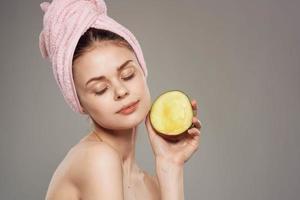 Smiling woman with bare shoulders with towel on head Mango in hand cropped view photo