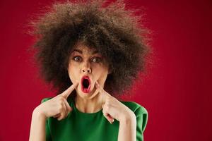 Portrait of a charming lady grimace afro hairstyle red lips fashion red background unaltered photo