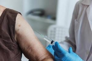 médico con un jeringuilla hace un inyección en el brazo inmunidad proteccion codicioso pasaporte de cerca foto