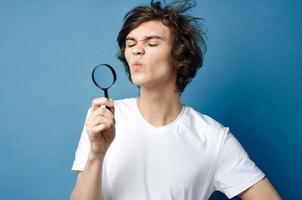 guy in a white t-shirt magnifying glass in his hands face problems photo