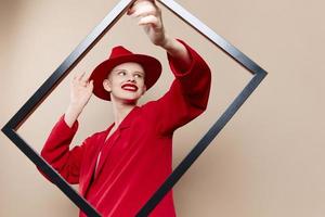 portrait of a woman frame in hand in red hat and jacket beige background photo