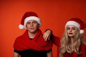 young couple in santa hats fun new year holiday red background photo