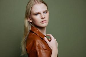Fashion offer for banner design. Closeup portrait of self-confident young female touching leather trench coat looks at camera at olive green studio wall background photo