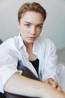 Women lying at home on the couch portrait with a short haircut in a white shirt, smile, depression in teenagers, home holiday photo