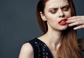 Woman in black dress touching face with hands and lipstick stress irritability photo