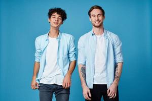 curly guy in a blue shirt and a blond man on a blue background communication friends fun photo