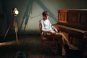 chico sentado cerca el piano posando estudio destacar foto