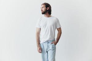 Portrait of a sad man with a black thick beard and long hair in a white t-shirt on a white isolated background photo