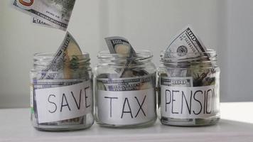 Masculin main met 100 dollars dans une verre pot avec le texte sauvegarder, impôt , Pension . concept de économie argent. video