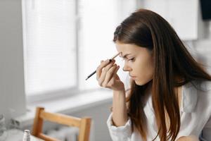 woman with pencil eyeliner foundation makeup at home photo