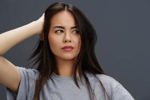 pretty woman with long hair in a gray T-shirt gesturing with hands Gray background photo