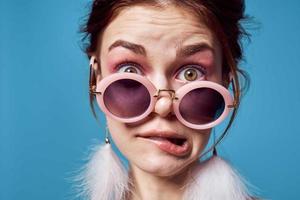 emotional woman wearing sunglasses fluffy earrings jewelry close-up blue background photo