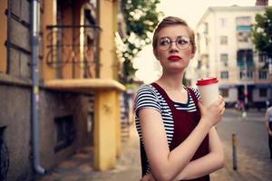 pretty woman with short haired glasses outdoors a cup of drink photo