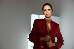 mujer modelo en un rojo chaqueta posando en un oscuro habitación Copiar espacio foto