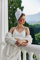 Woman in a bathrobe with a towel on his head patches on his face stands on the balcony unaltered photo