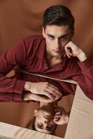 a man in a shirt sits at a table reflection in a mirror fabric background photo