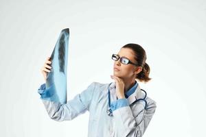 hembra médico profesional en un blanco Saco mirando a un radiografía a un profesional foto