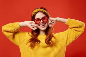 woman in yellow sweater wearing red glasses headband fashion red background photo