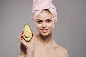 Cheerful woman with a towel on her head cropped view of an avocado in her hand photo