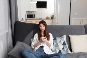 woman with a phone in her hands sitting on a comfortable sofa leisure weekend technology photo