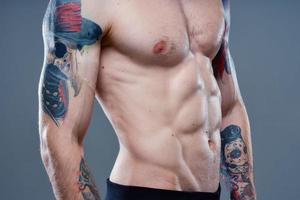 sexy athlete with naked torso and pumped up muscles tattoo gray background model photo