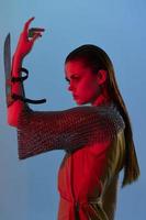 young woman Glamor posing red light metal armor on hand blue background photo