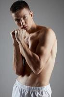 athlete with pumped-up torso gesturing with hands on gray background cropped view portrait photo